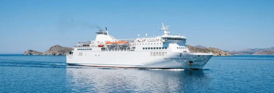 Un moderno traghetto bianco naviga in mare aperto sotto il sole del Mediterraneo con cielo azzurro